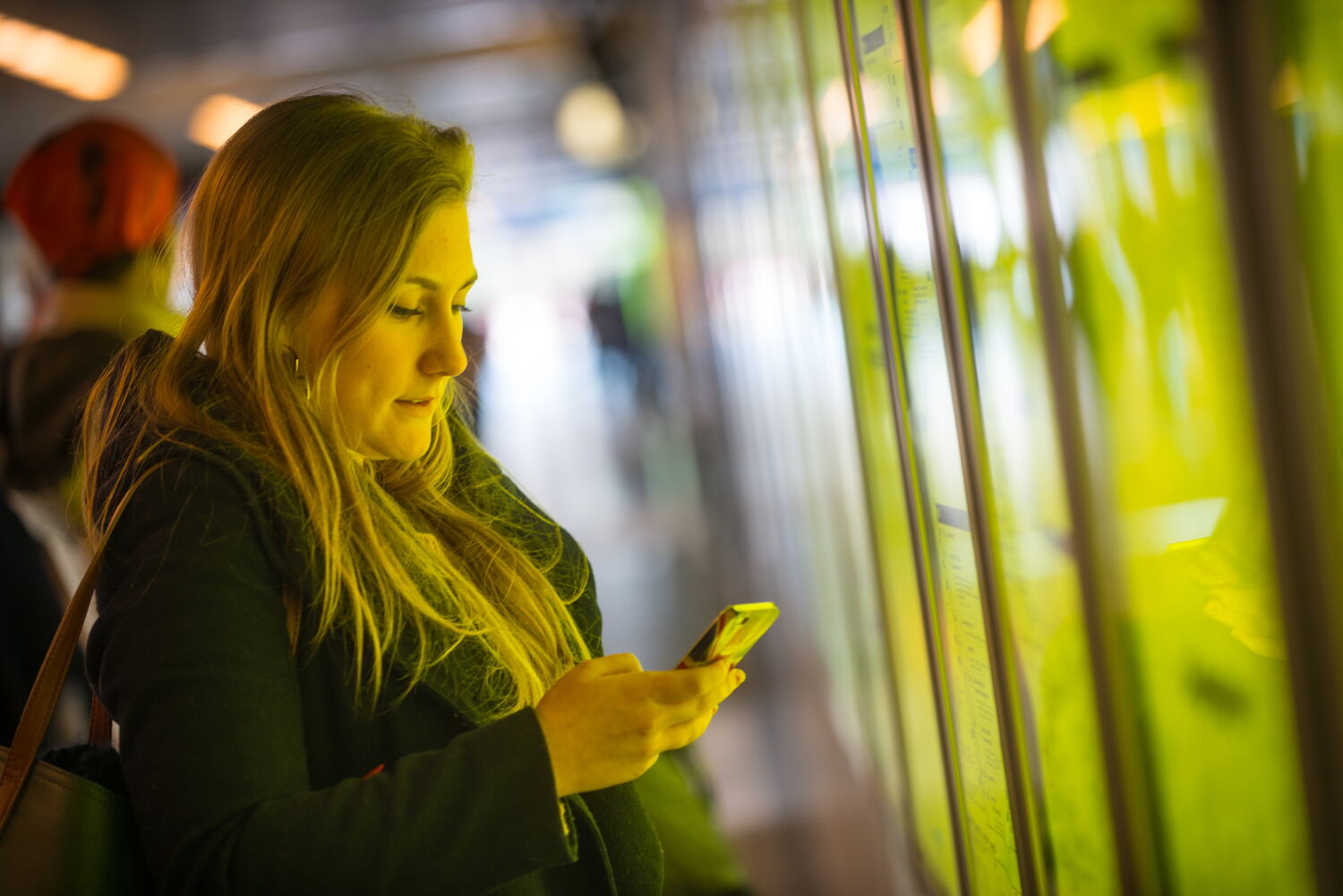 jonge dame zoekt informatie op smartphone aan een treintabel