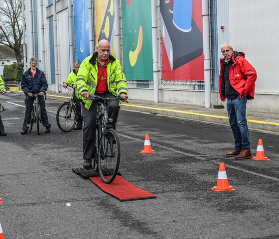 lesgever geeft instructies aan twee fietsers die een lesparcours volgen